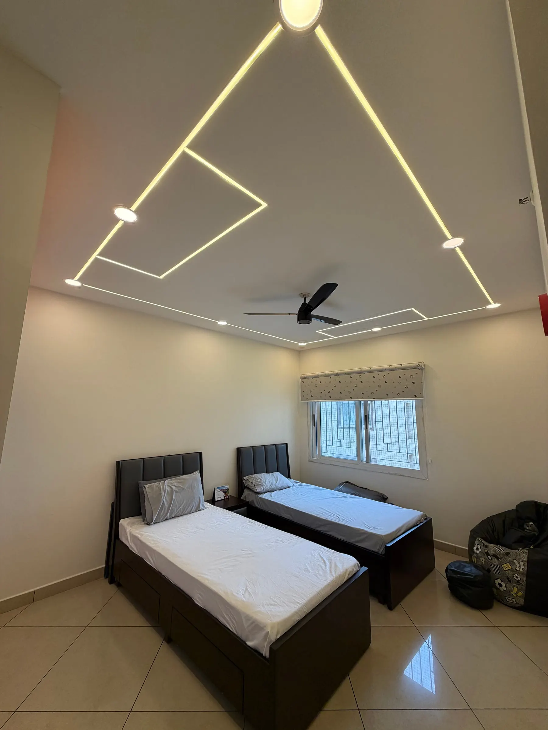 Bedroom ceiling with lines of light forming a triangle above twin beds and a window