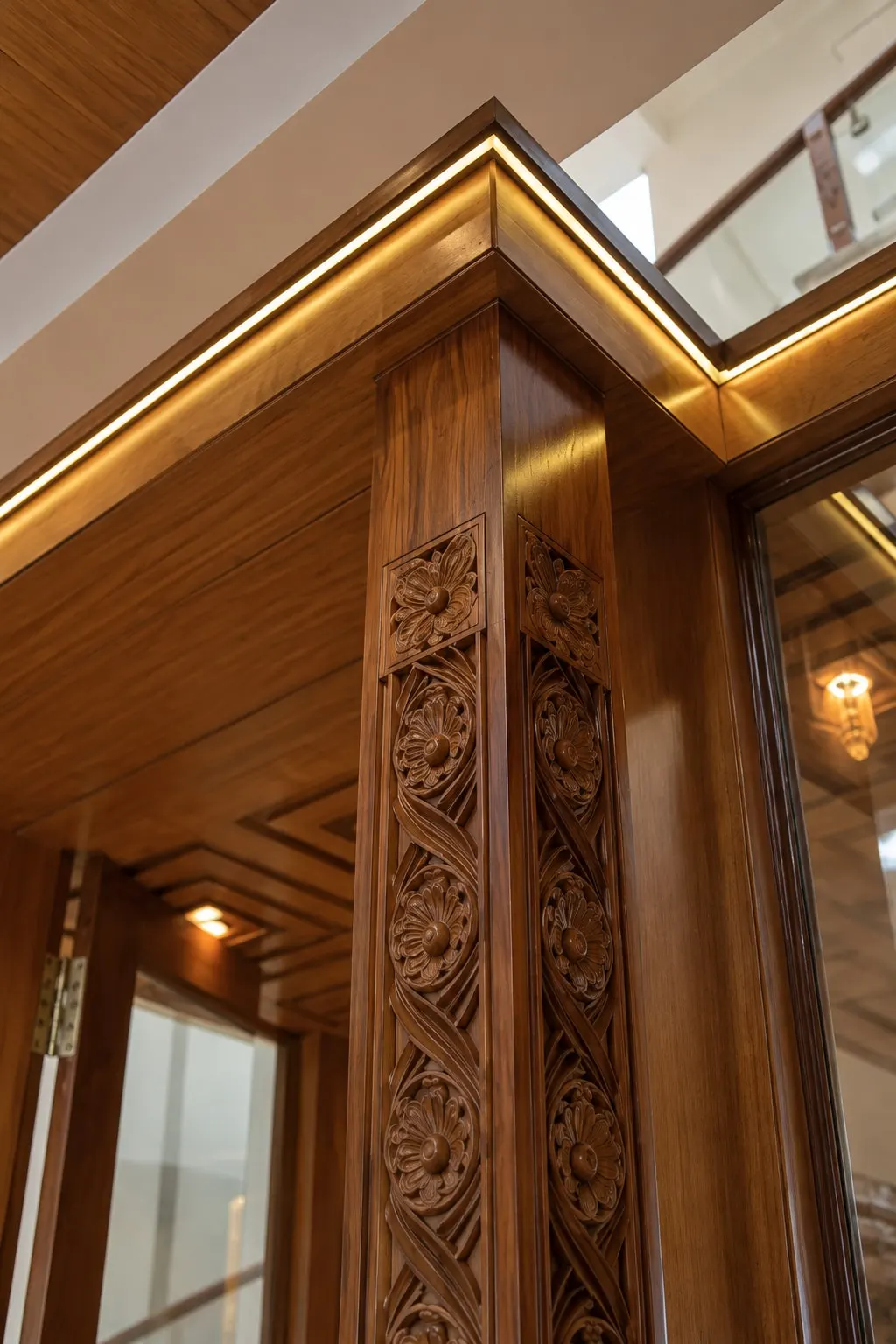 A carved timber pillar with floral motifs under a timber cornice lined with light