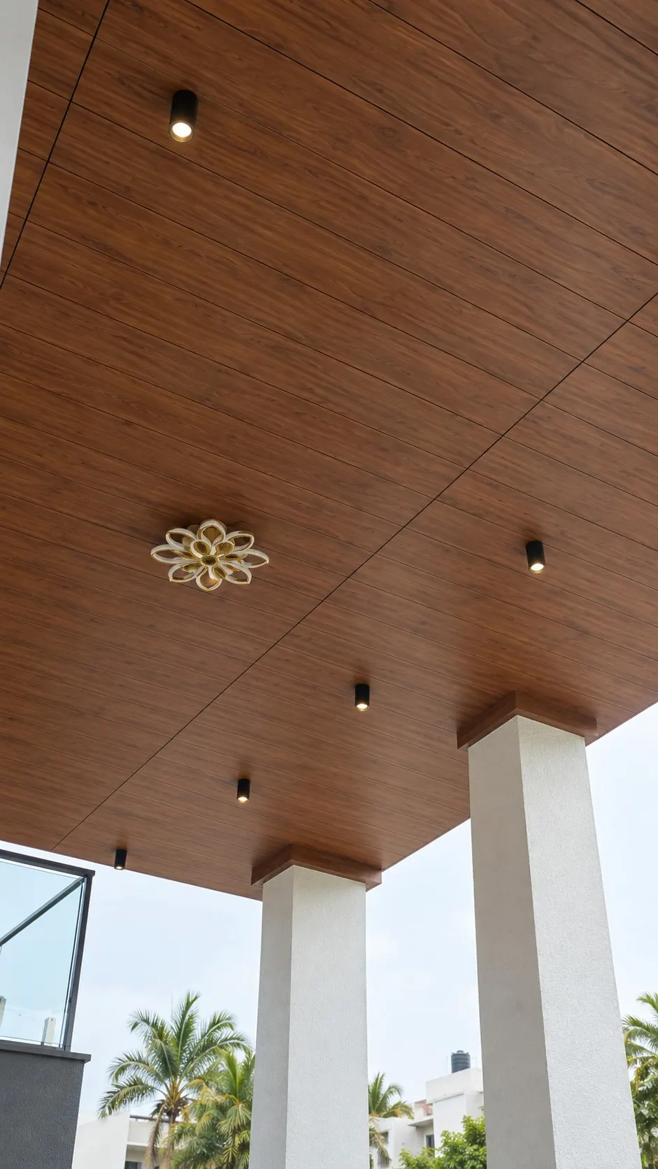 Porch ceiling in timber finish with spotlights and a flower-shaped fitting, carried on square white pillars